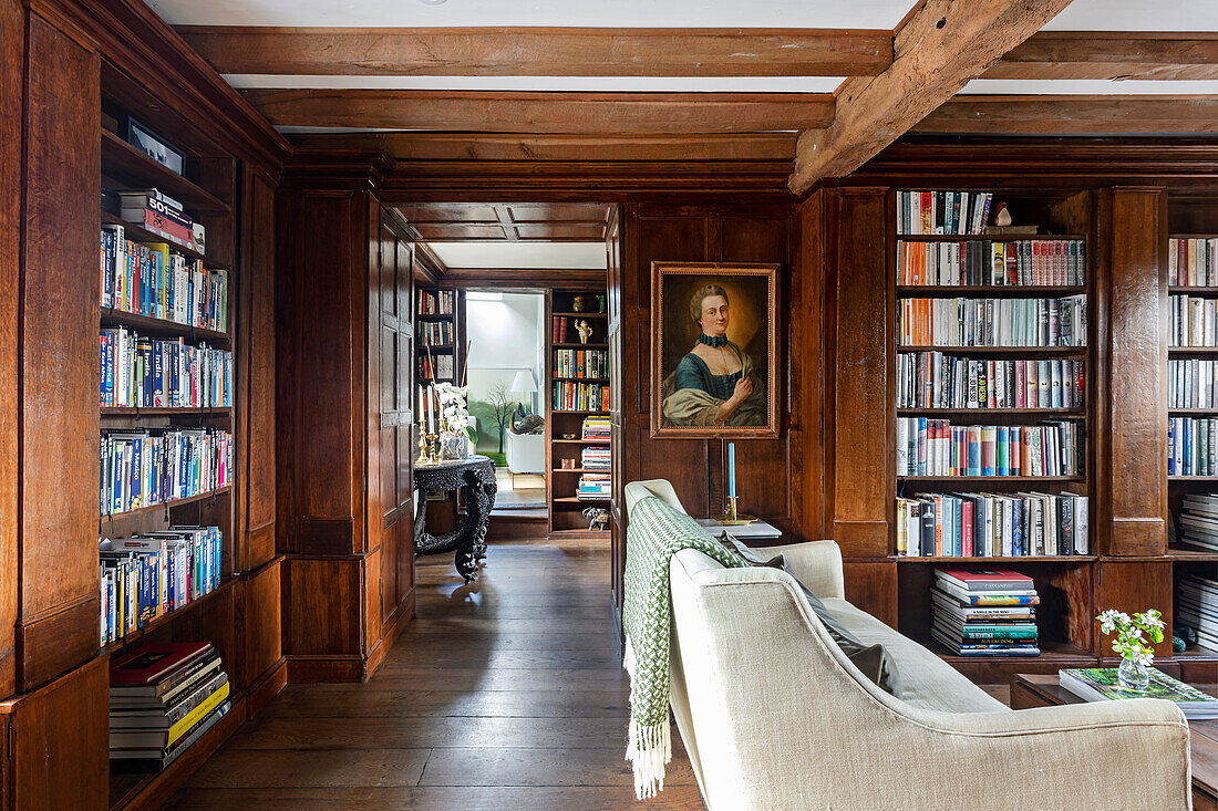 Wooden library with cream-colored sofa and historical portrait on the wall