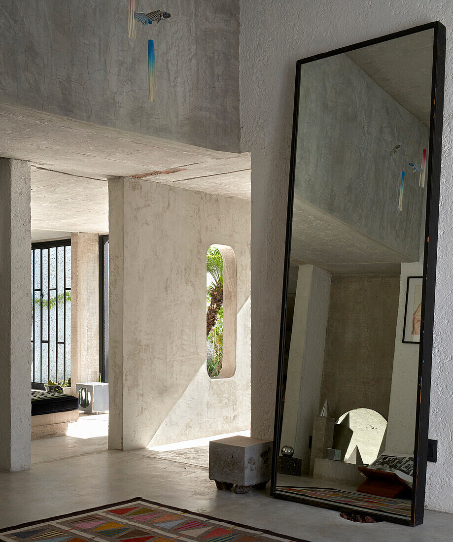 Loft mit Betonwänden, großer Spiegel und Teppich mit und geometrischem Muster im Eingangsbereich