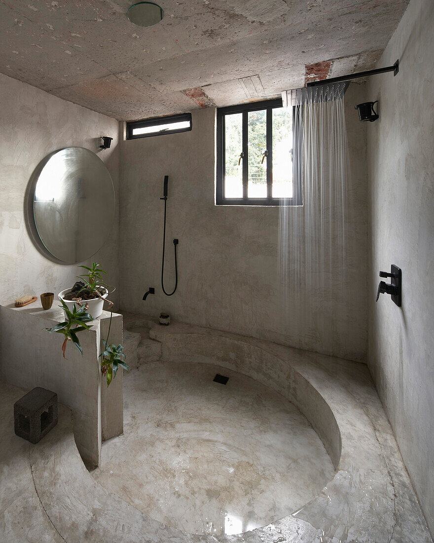 Runddusche im minimalistischen Badezimmer mit Betonwänden