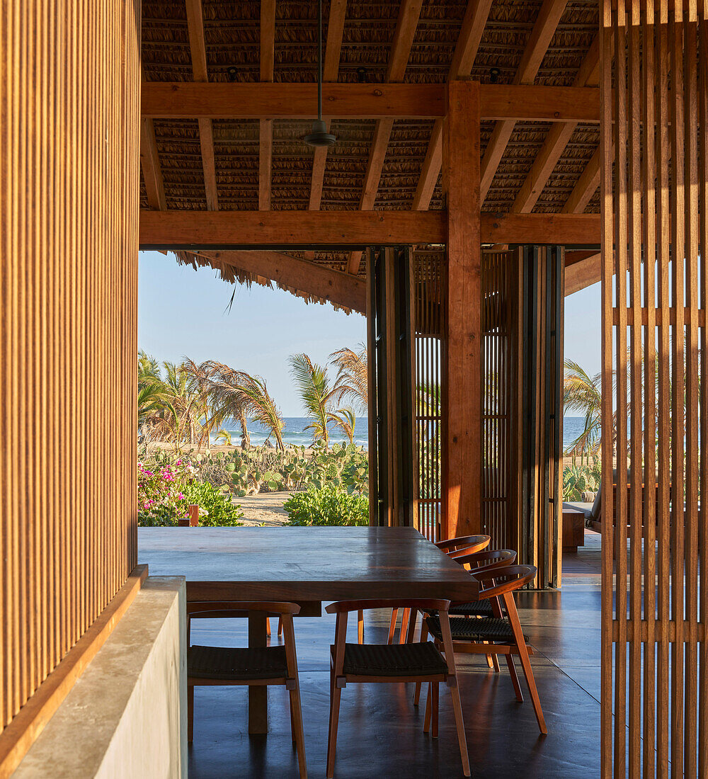 Essbereich mit Holzelementen im Strandhaus mit Blick auf das Meer