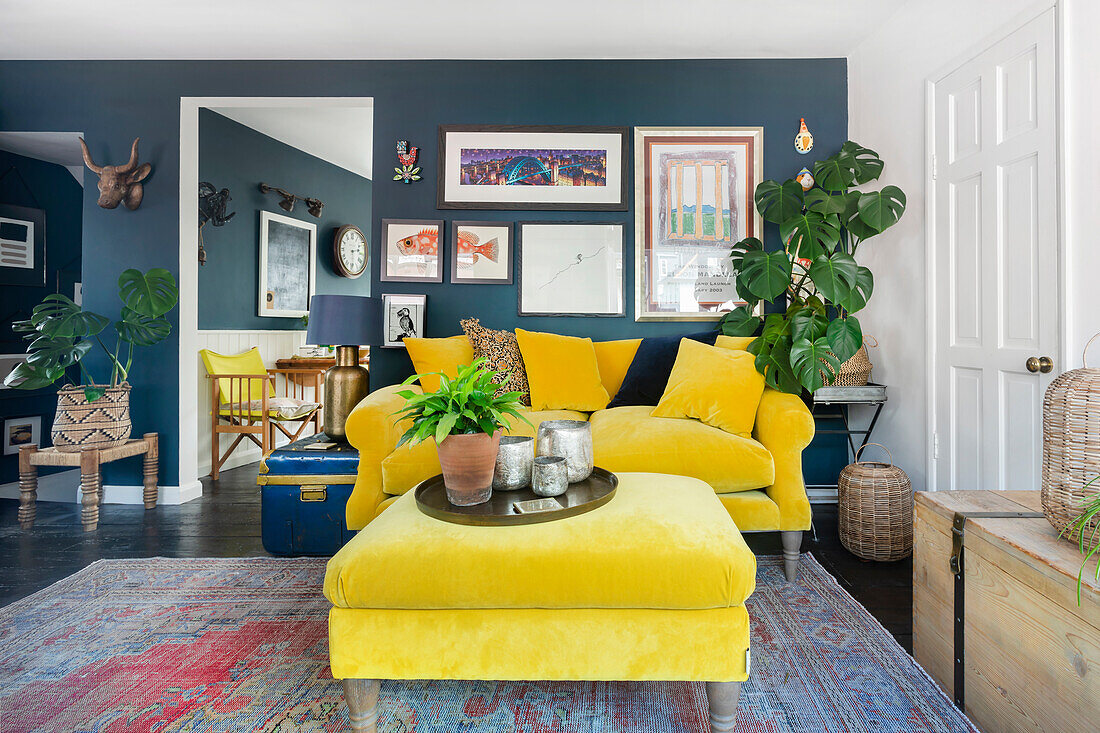 Yellow velvet sofa in modern living room with blue wall and plants