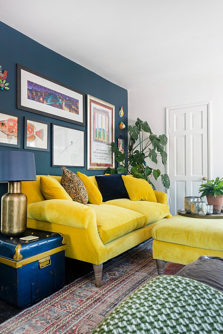 Yellow sofa in front of dark blue wall with framed pictures in living room