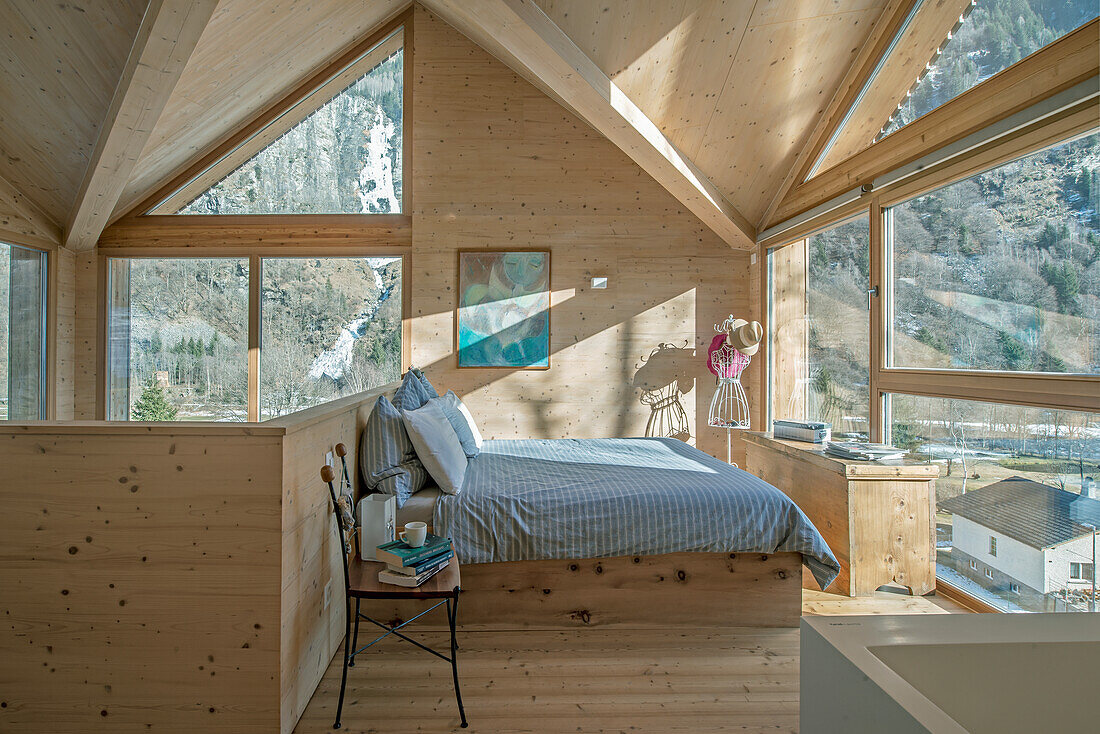 Schlafzimmer in Holzoptik mit Panoramafenstern und Bergblick