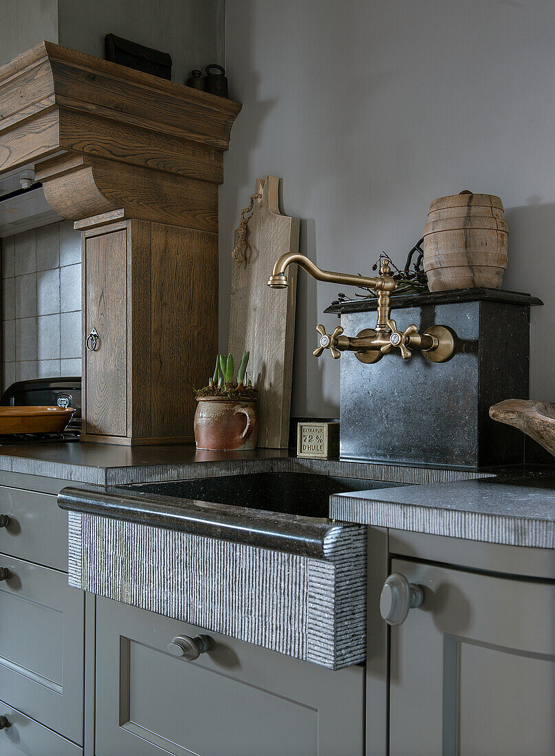 Rustic kitchen area with unusual stone sink and brass mixer tap