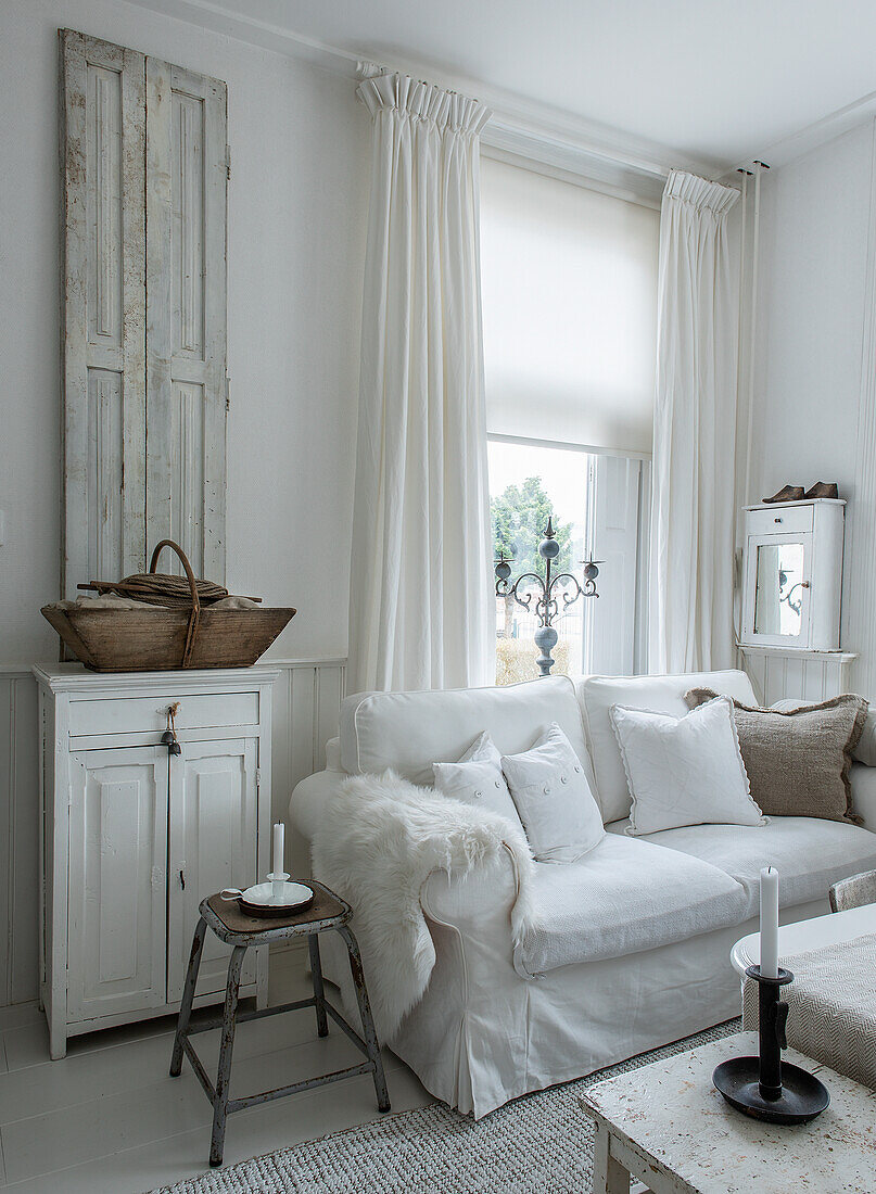 Living room with white sofa, shabby chic decor and old wooden furniture