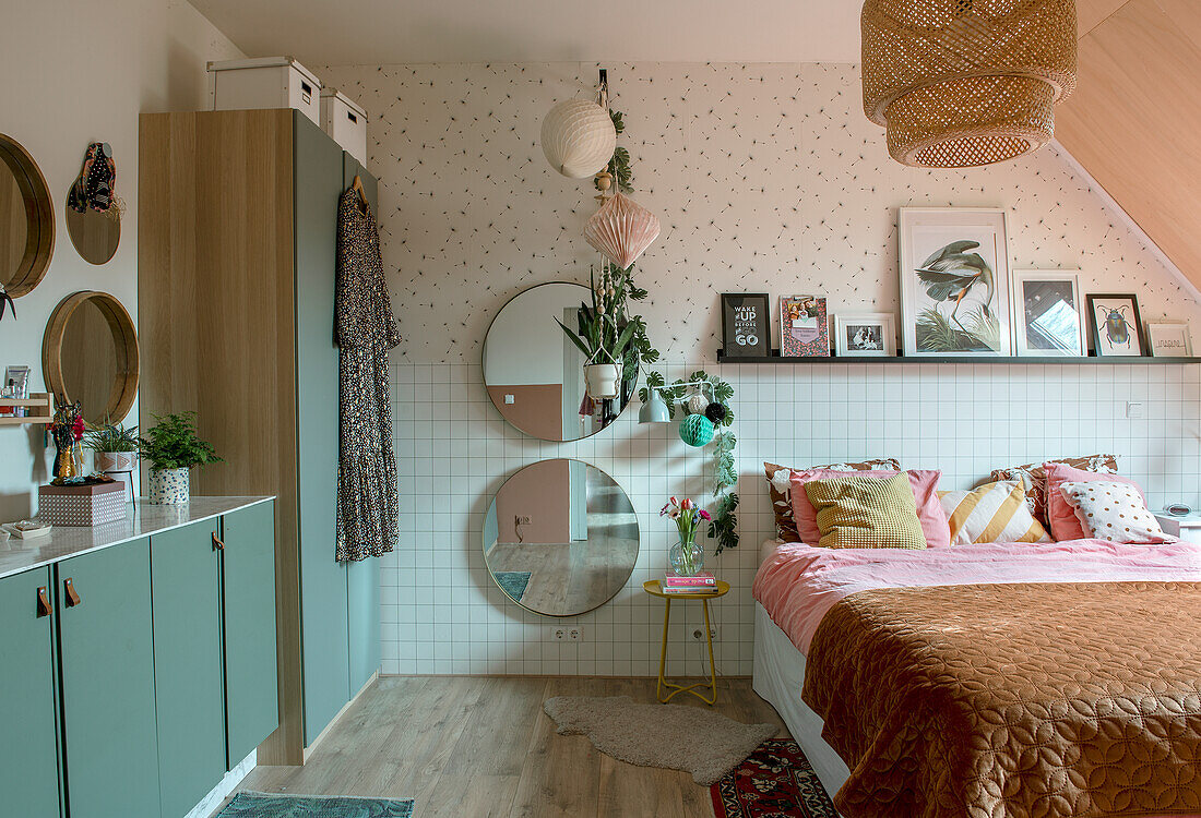 Bedroom with green wardrobes, round mirrors and picture shelf