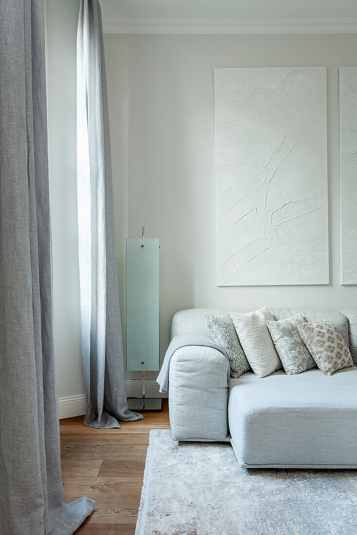 Light grey sofa with patterned cushions and abstract mural in modern living room