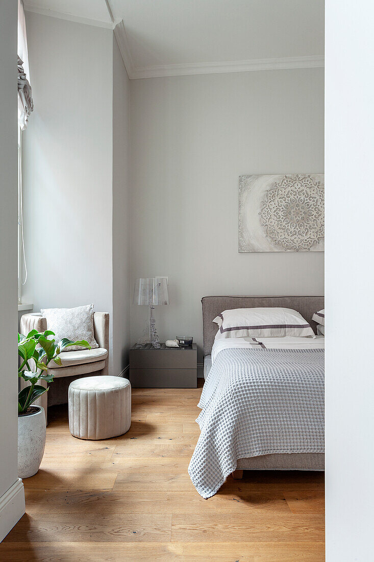 Bedroom with wooden floor, grey bed and white seating furniture