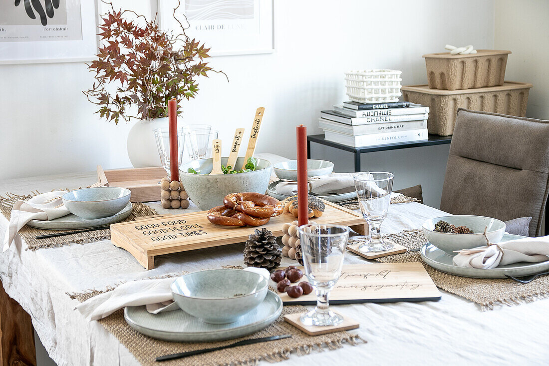 Gedeckter Esstisch mit Holzbrett mit Schriftzug und herbstlicher Dekoration