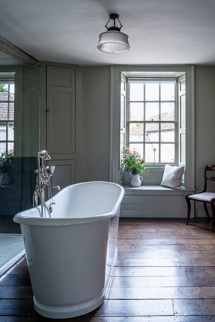 Freestanding vintage bathtub in the bathroom with window seat