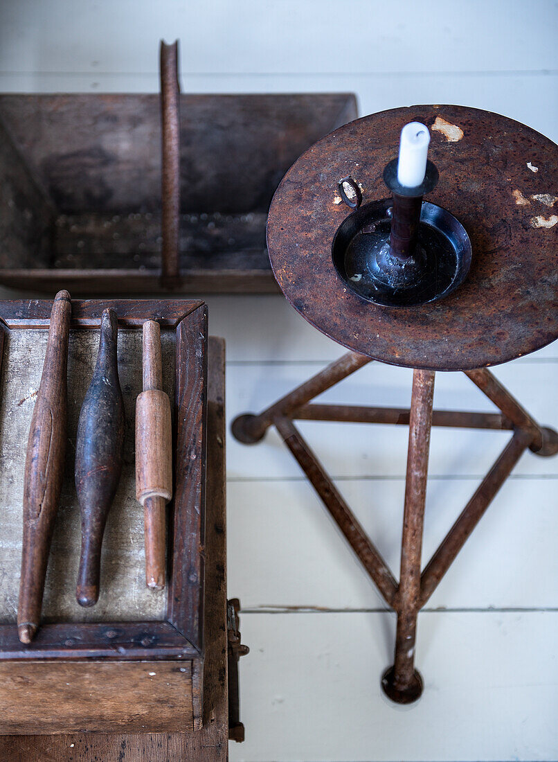 Antique sewing bobbins next to candlestick on rusty metal stool