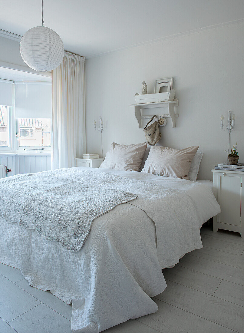 Bright bedroom with double bed and white bed linen, hanging lamp and window with curtains