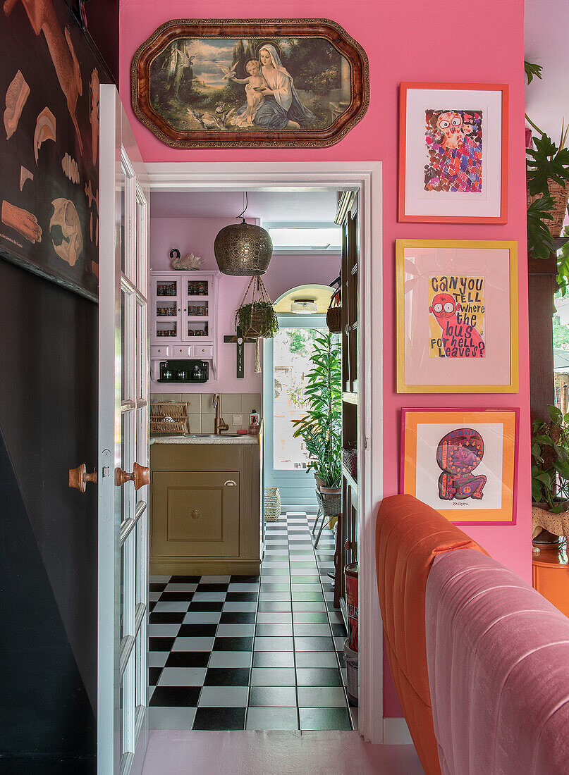 Colorful hallway with pink and orange tones and artwork with a view of the kitchen with checkerboard flooring