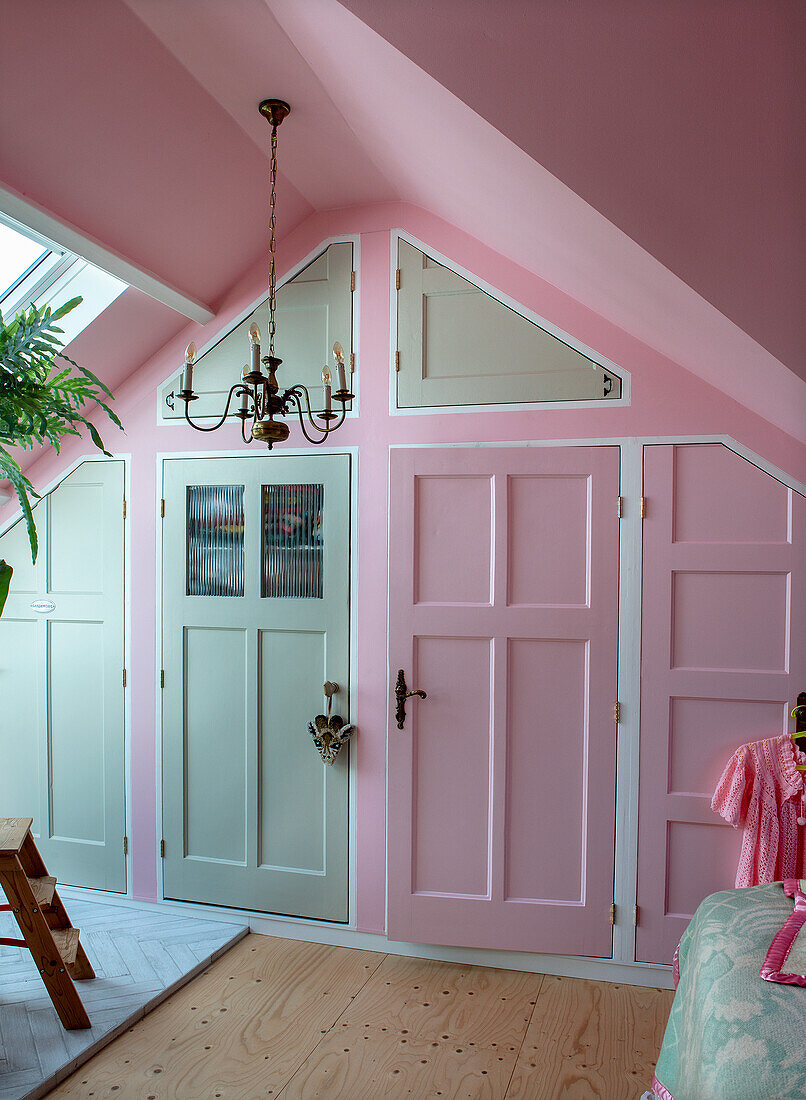 Attic room with pink walls, white doors and antique chandelier