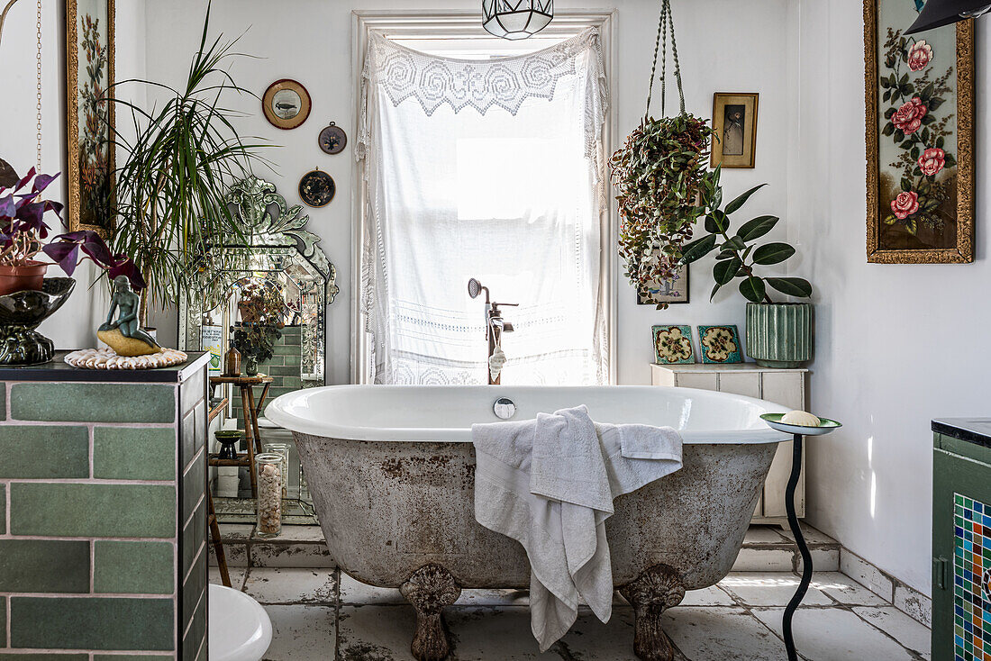 Freestanding vintage bathtub with flower and plant arrangements in the eclectic bathroom