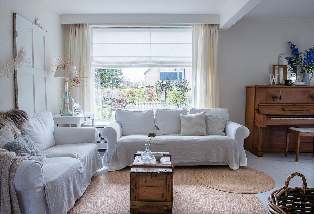 Bright living room with white sofas, piano and window front