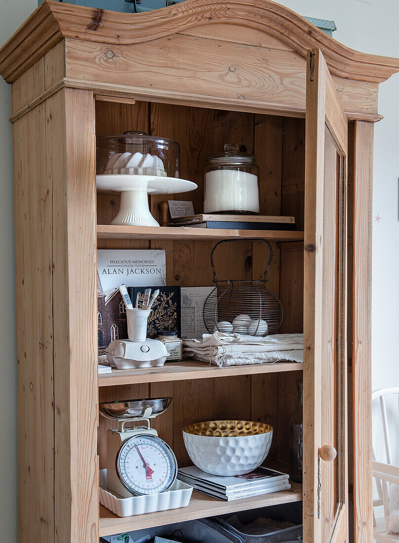 Open wooden cupboard with kitchen utensils and decorative elements