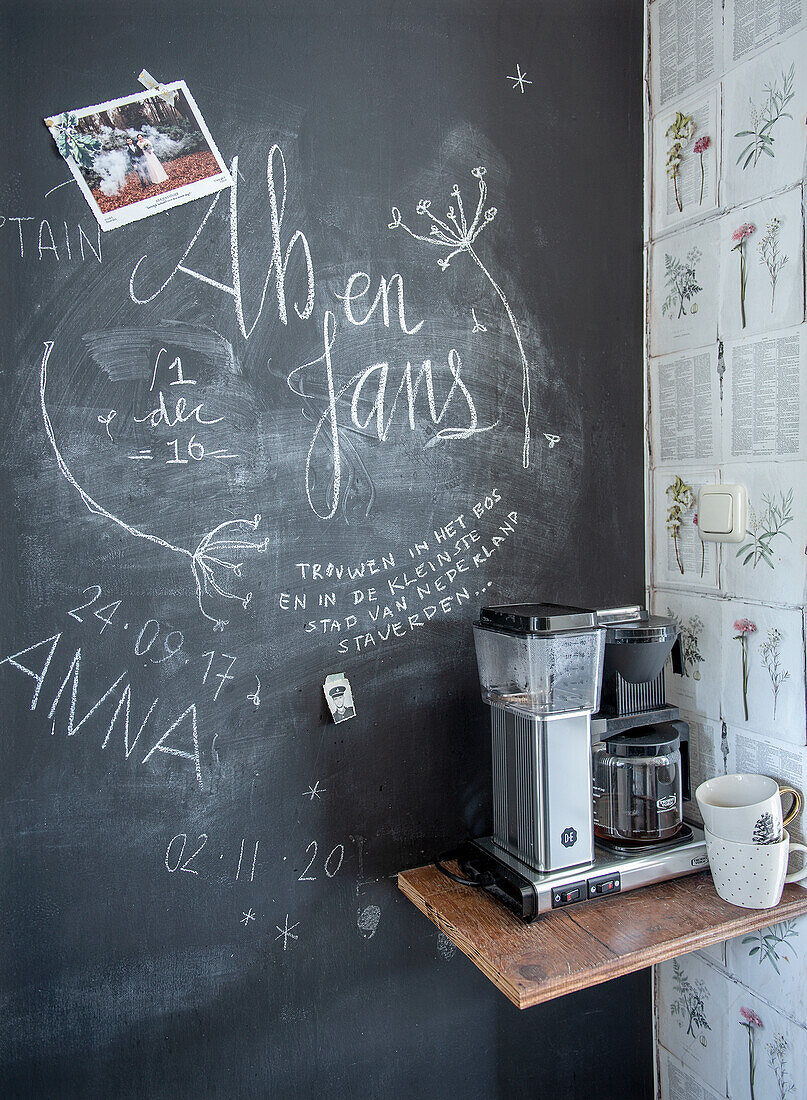 Coffee machine on wall shelf in front of chalkboard wall in the kitchen