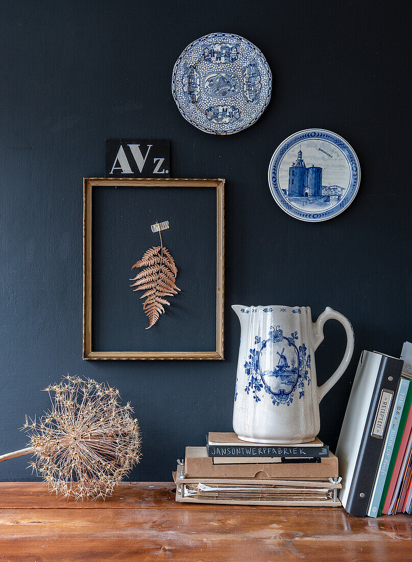 Vintage decoration with blue and white ceramic plates and antique jug against a dark wall