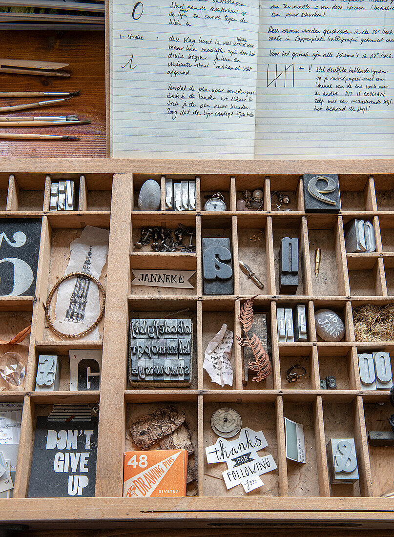 Schriftsetzkasten mit verschiedenen Buchstaben und Accessoires auf einem Schreibtisch