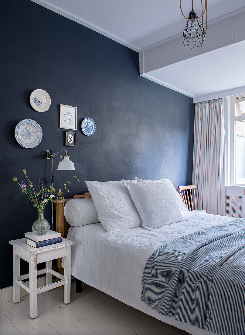 Bedroom with dark accent wall and white tones, decorated with wall plates