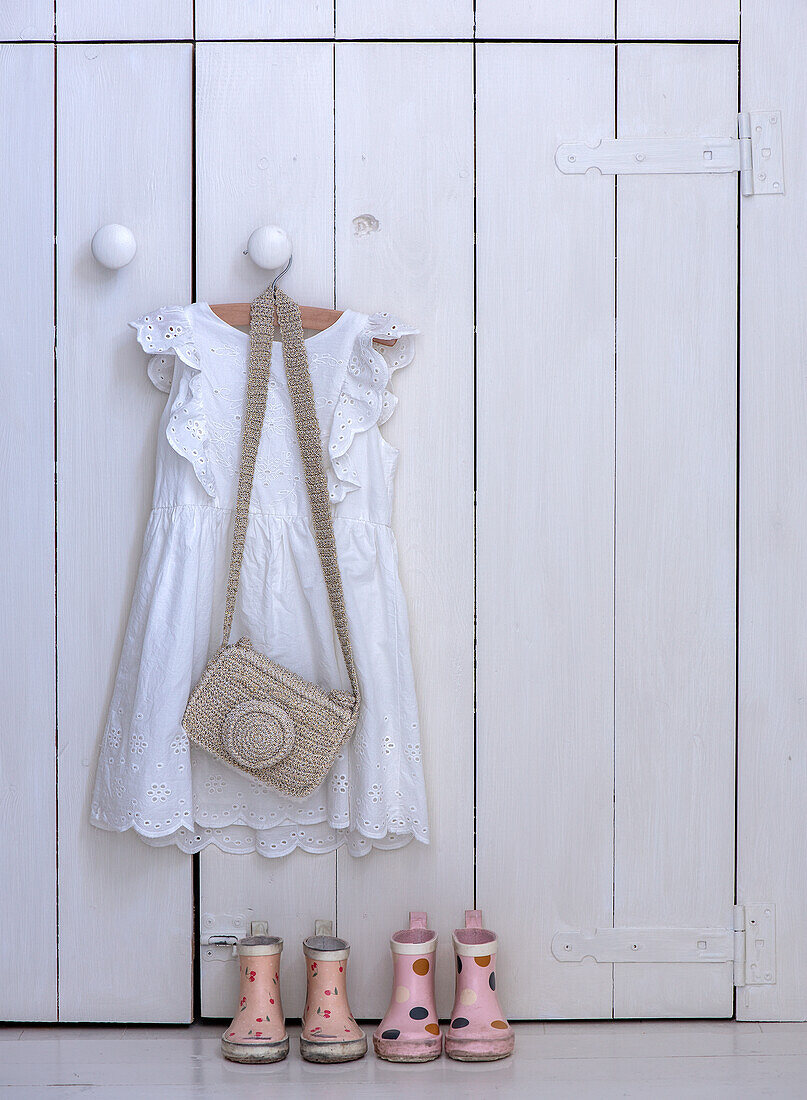 White children's wardrobe with lace dress, raffia bag and wellies