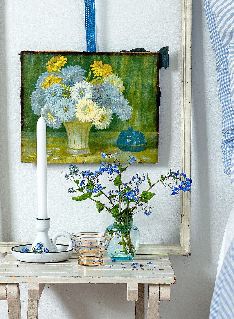 Side table with candle holder, vase with forget-me-nots and flower painting