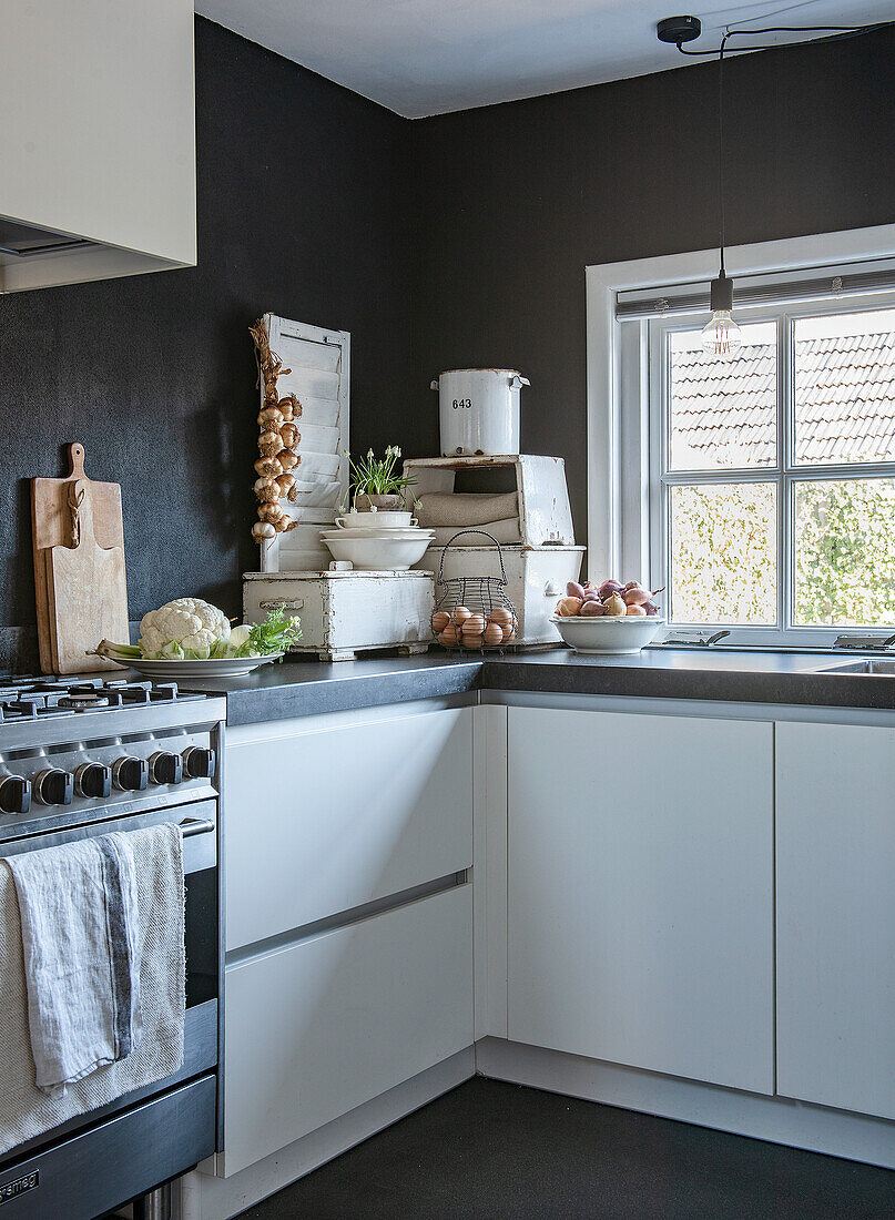 Kitchen corner with white cupboards, black walls and retro decorations