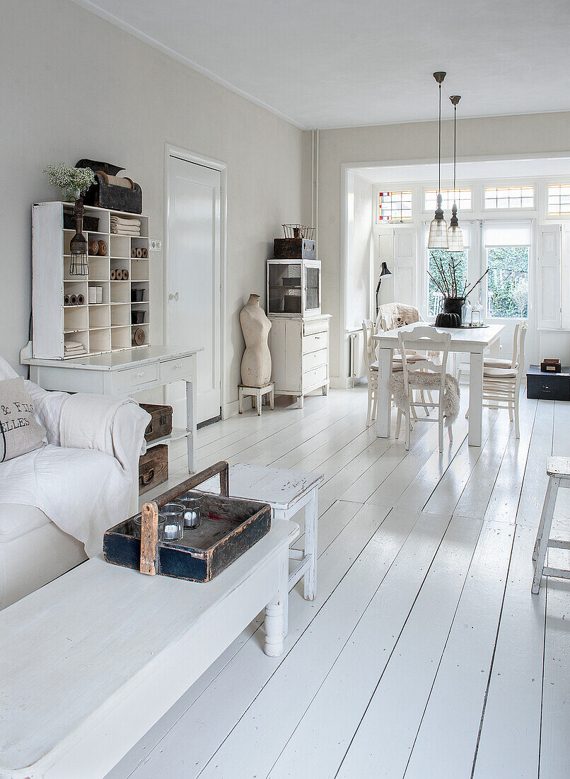 Bright Scandinavian-style living-dining room with white wooden floors and furniture