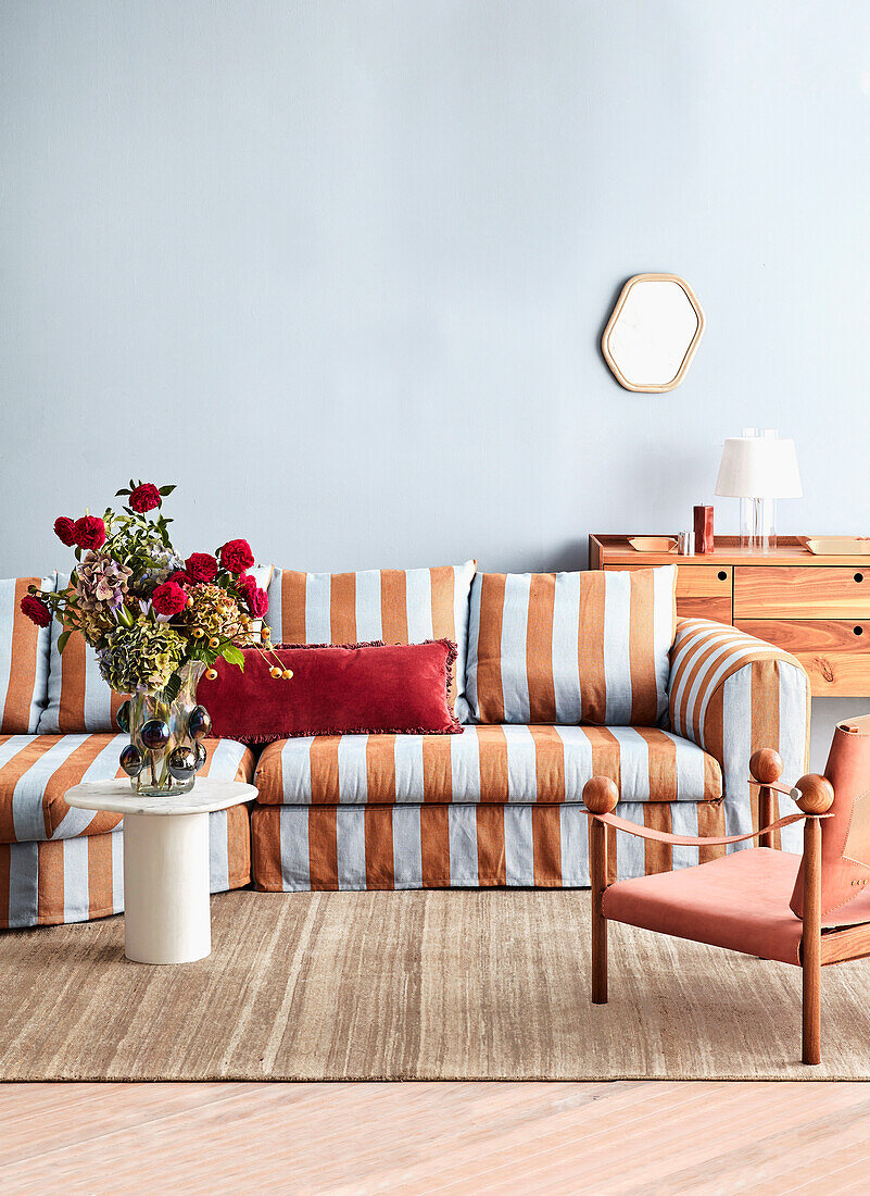 Striped couch with red accent pillow and flower arrangement on coffee table, living room