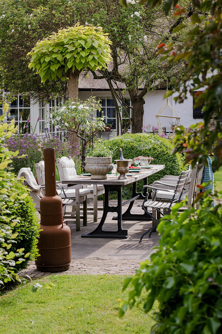 Gedeckter Gartentisch im grünen Innenhof mit Kaminofen