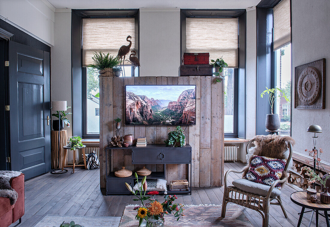 Wohnzimmer mit rustikaler Holzwand, Metall-Sideboard und Rattanstuhl