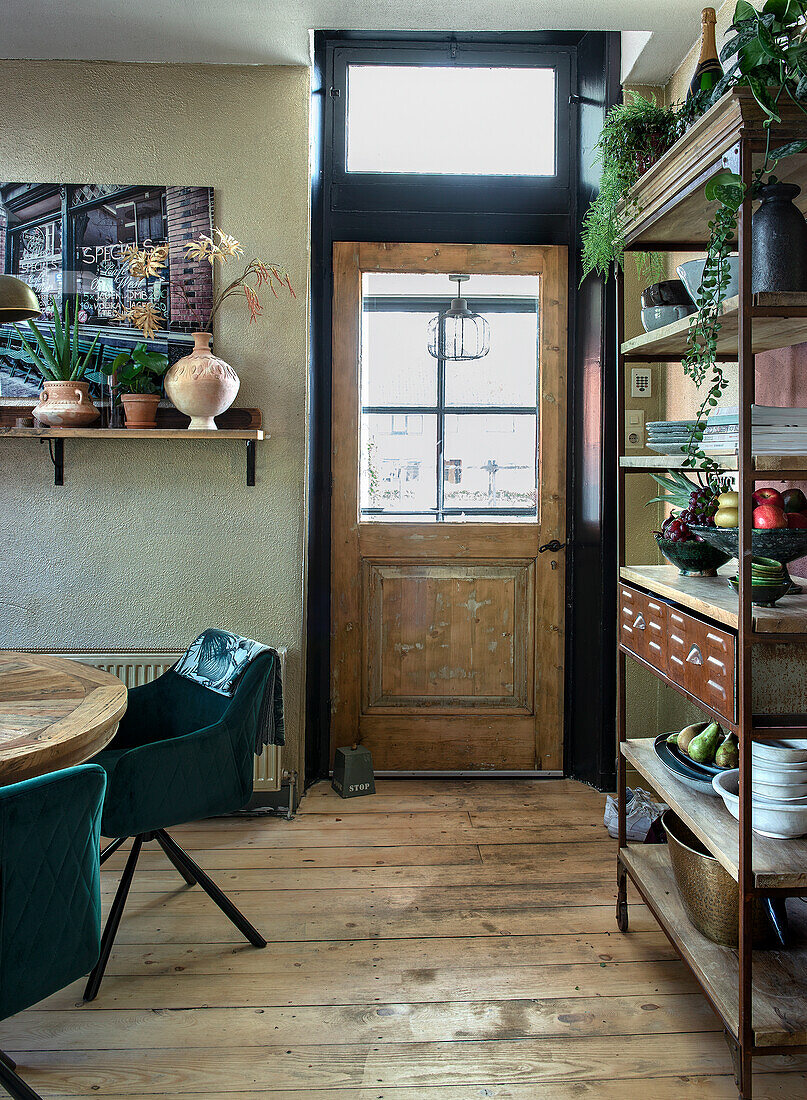 Dining area with wooden shelf, round dining table and green velvet chairs