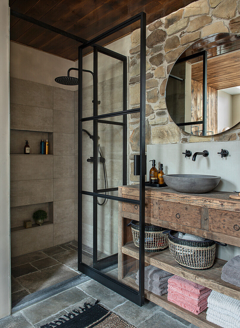 Rustic bathroom with natural stone wall and glass shower stall