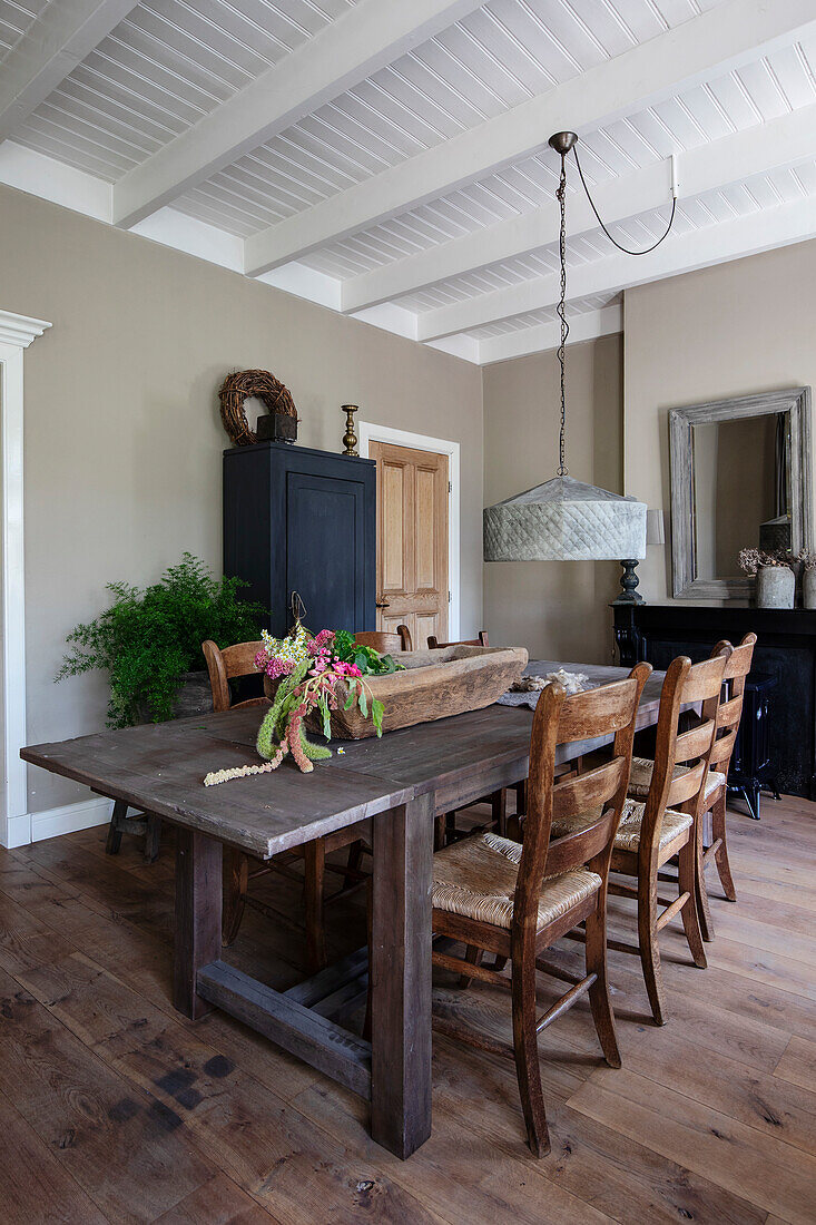 Dining room with rustic table, wooden chairs and grey pendant lamp