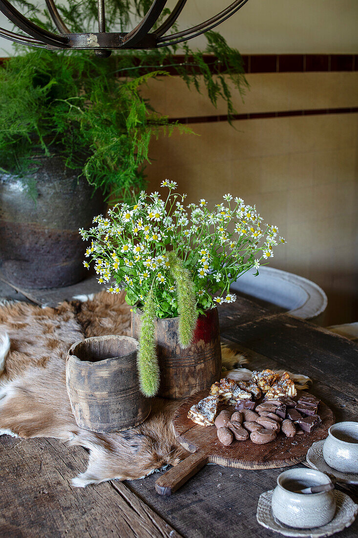 Rustikaler Holztisch mit Wildblumenstrauß und Schokoladenstücken auf Holzbrett