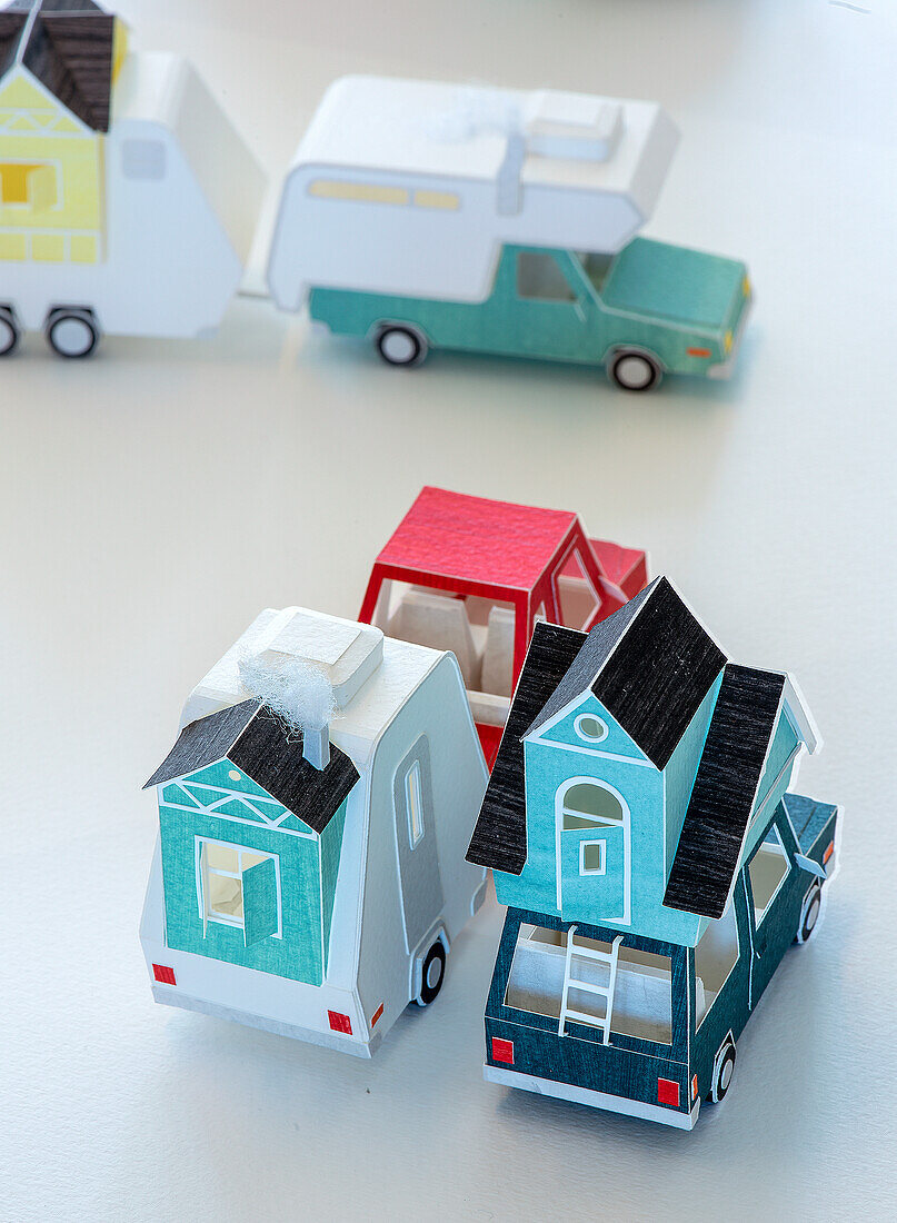 Paper models of cars and caravans on a white table