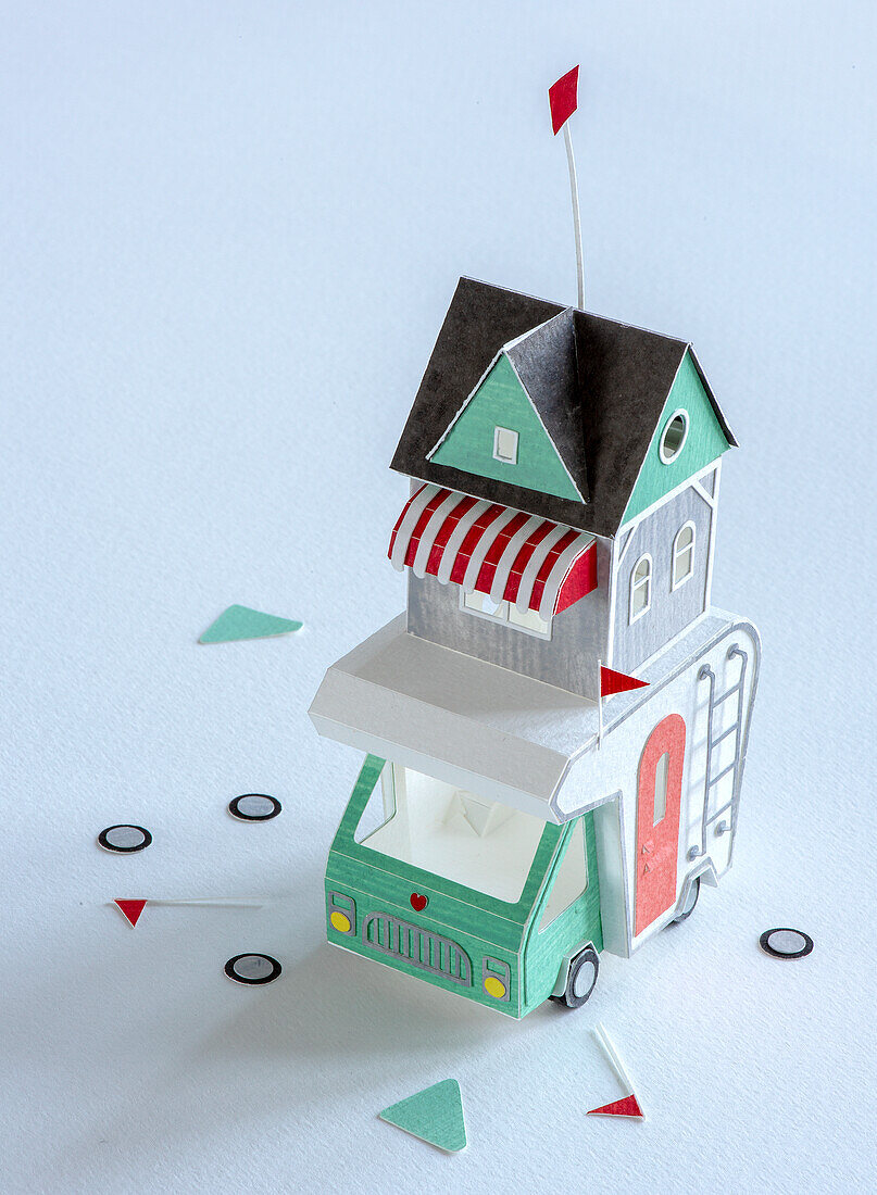 Paper model of a colourful caravan with a small house attachment