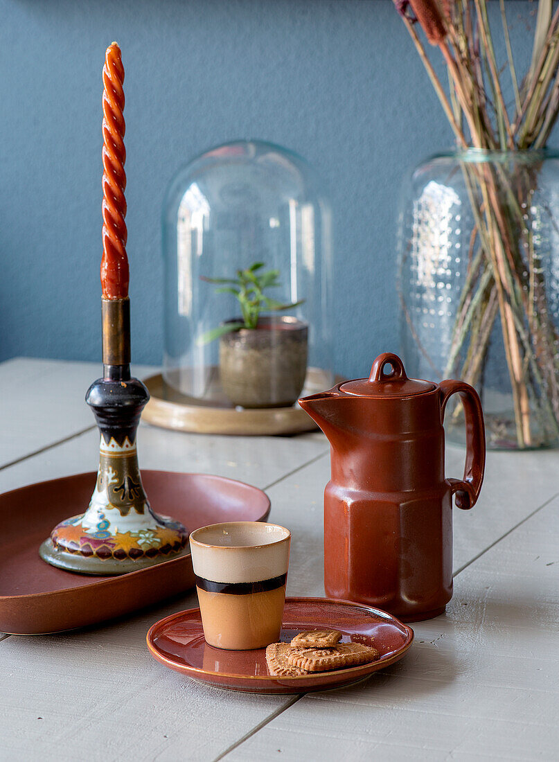 Kerzenhalter, Kaffeekanne und Tasse im Retro-Look auf weißem Holztisch