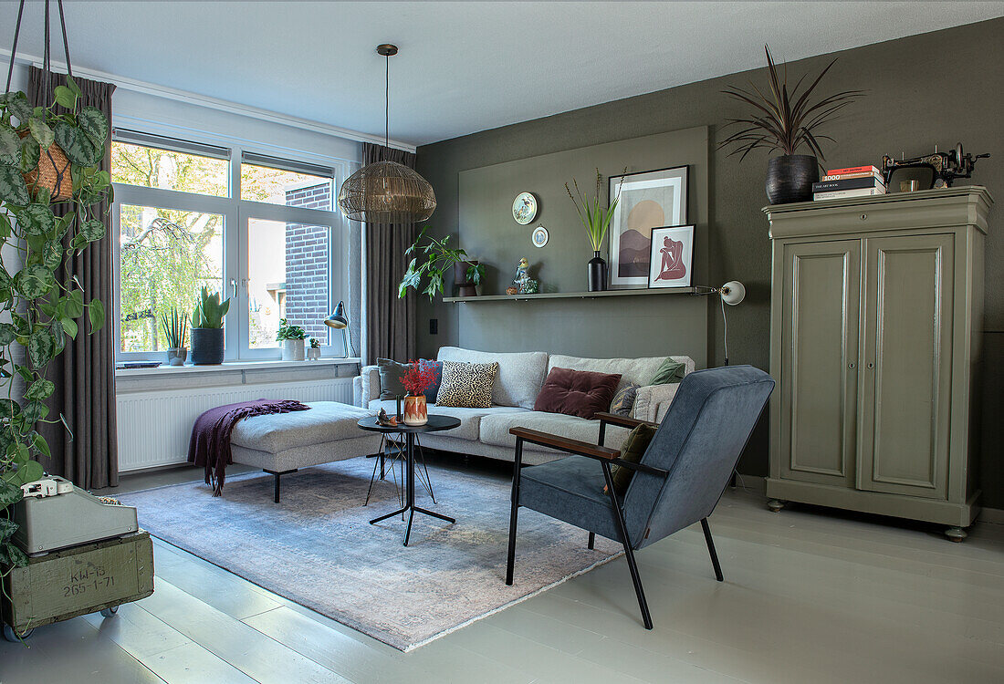 Living room with green accent wall, grey sofa and blue armchair