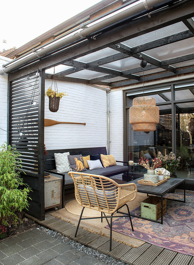 Covered terrace with lounge sofa, rattan chair and wooden table