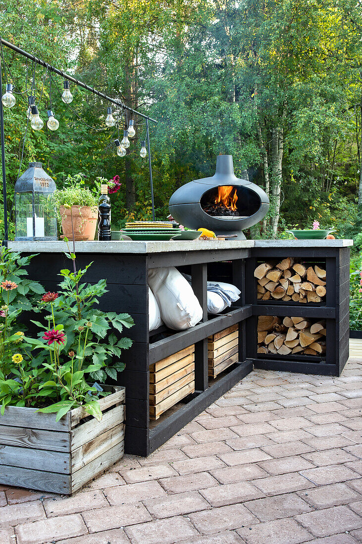 Outdoor kitchen with crockery, wood-burning stove and wood storage