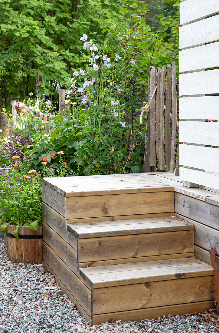 Holztreppe vor blühenden Stauden im Garten