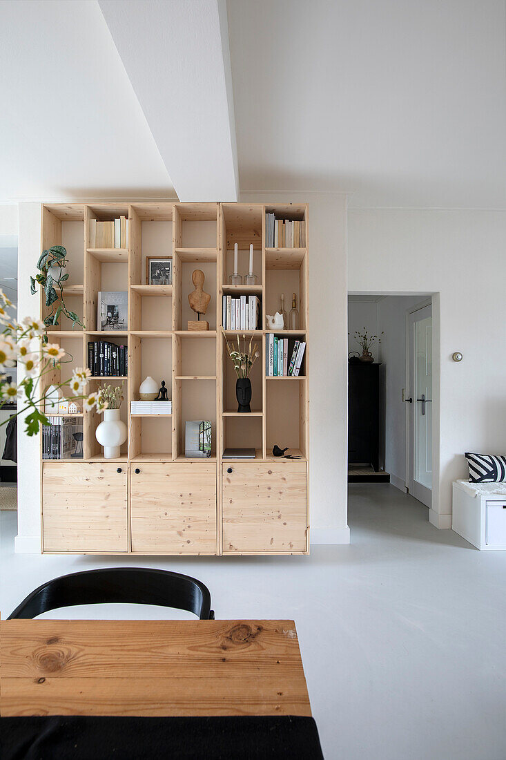 Bright living room with wooden shelving wall and view into hallway