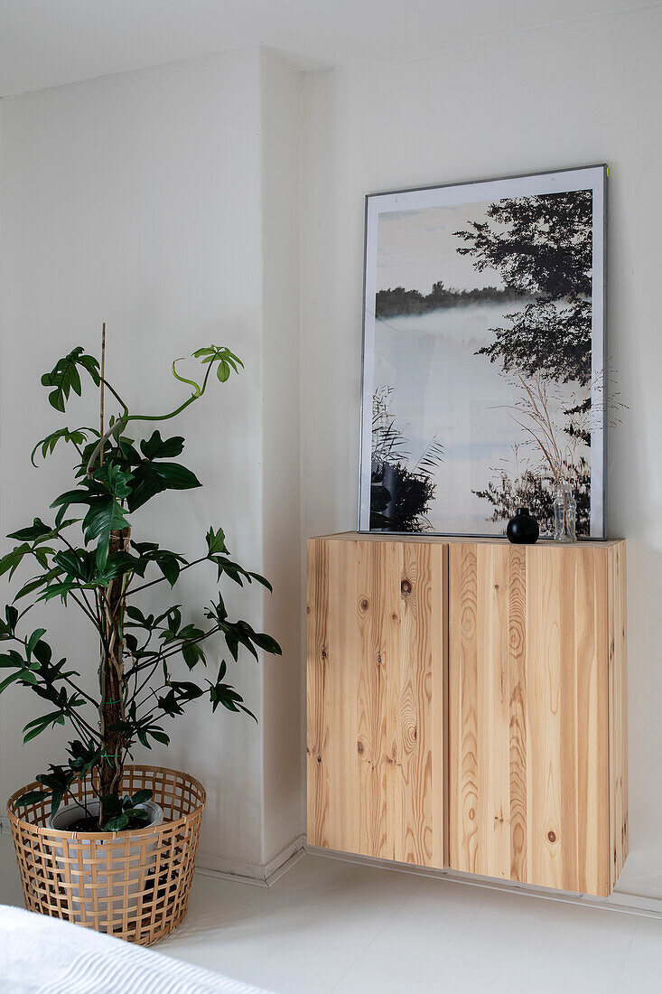 Floating pine dresser with framed landscape painting and houseplant in basket