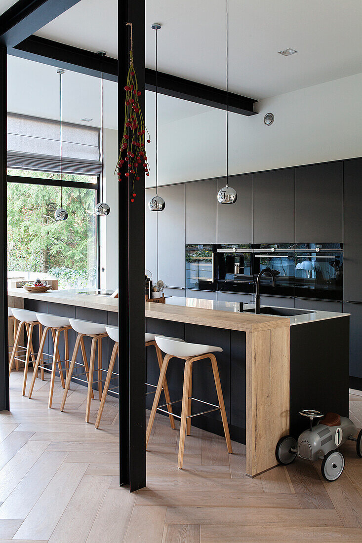 Modern kitchen with black front, wooden counter and wooden bar stools