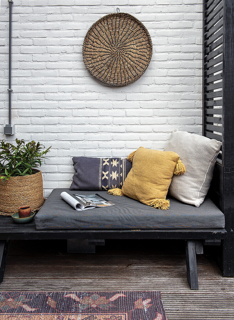 Garden lounge with colourful cushions and rattan wall decoration