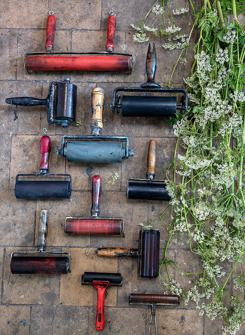 Vintage Farbwalzen und wilde Blumen auf Steinboden