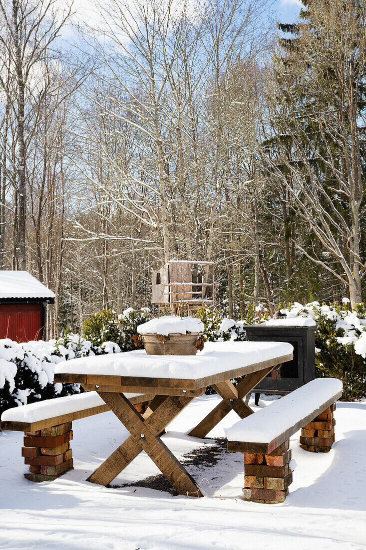 Snow-covered rustic wooden table in winter garden