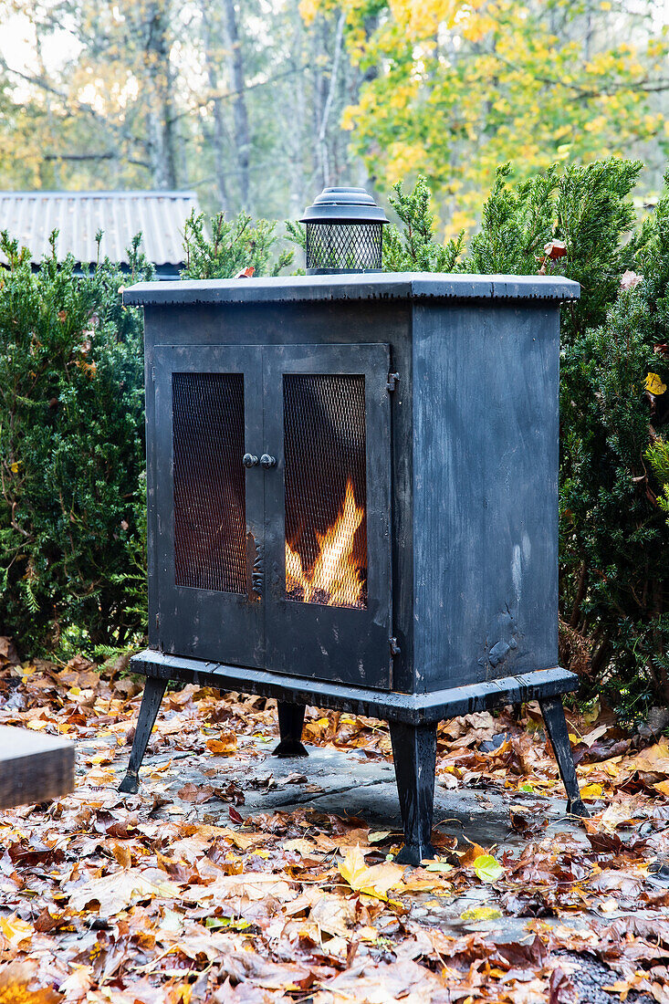 Black patio stove surrounded by autumn leaves in the garden